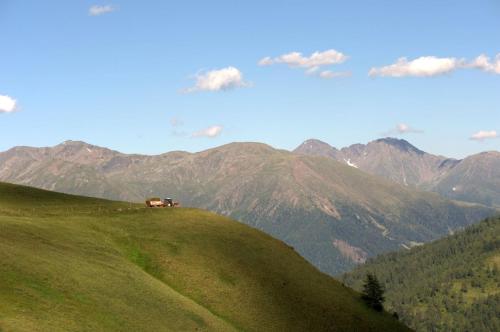a house on a hill with mountains in the background at Almhütte Oberschaller bei Alfenalm - Ferienwohnungen am Berg in Innervillgraten