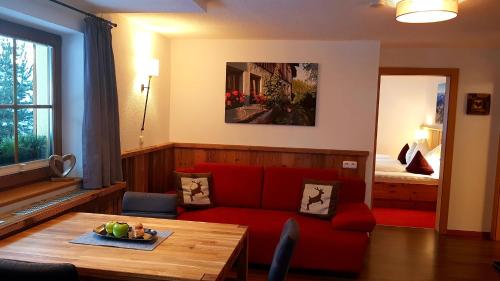 a living room with a red couch and a table at Landhaus Sonneck in Pettneu am Arlberg