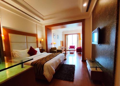 a hotel room with a bed and a television at Ambrosia Sarovar Portico in Haridwār