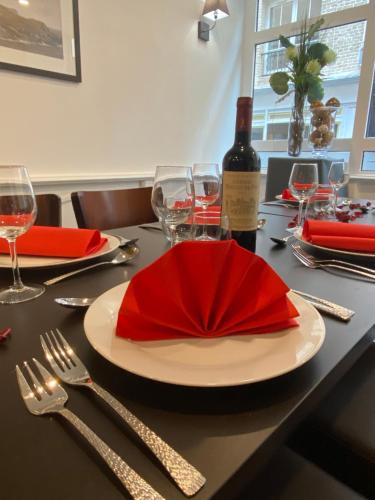 una mesa con una servilleta roja y una botella de vino en Hôtel Au Grand Duquesne, en Dieppe