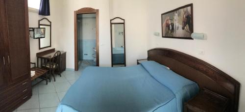 a bedroom with a blue bed and a bathroom at Hotel Castiglione in Ischia