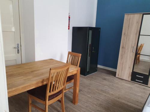 a dining room with a table and chairs and a refrigerator at Ferienwohnungen am Stadtpark in Norden