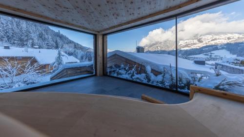a room with a large window with snow covered mountains at Das Kaltenbach - ApartHotel in Kaltenbach