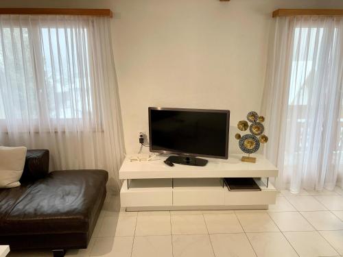 a living room with a television on a white table at Bergröschen in Saas-Grund