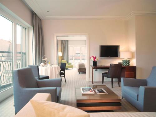 a living room filled with furniture and a tv at Rocco Forte The Charles Hotel in Munich