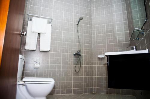 a bathroom with a shower with a toilet and a sink at Millenium Popo Beach Hotel in Grand-Popo