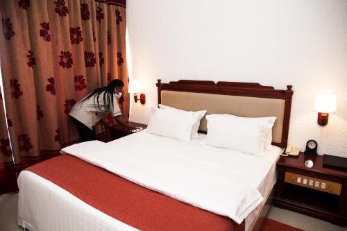 a woman standing next to a bed in a hotel room at Millenium Popo Beach Hotel in Grand-Popo