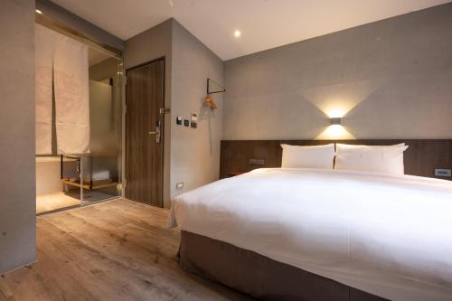 a bedroom with a large white bed and a sliding glass door at Yunoyado Onsen Hot Spring Hotel Deyang in Jiaoxi