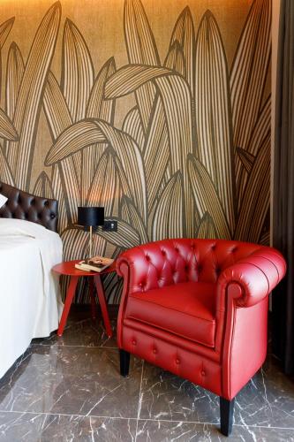 a red leather couch in a bedroom with a wall at Deville & Spa in Costermano sul Garda