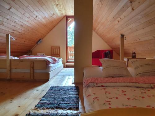 un dormitorio en el ático con 2 camas y una ventana grande en MOUNTAIN ECO CHALET KONJSKA DOLINA on 1400 m asl -near Pokljuka, en Srednja Vas v Bohinju