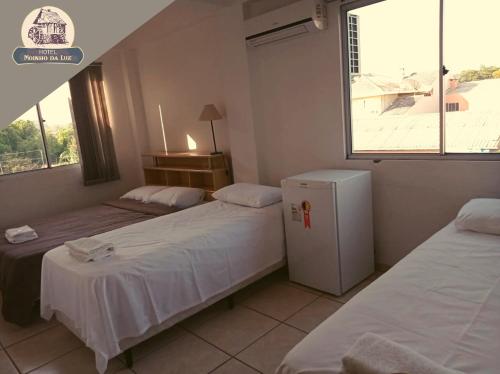 Hotel Moinho da Luz - 10 minutos de Lajeado في Arroio do Meio: غرفة بسريرين وثلاجة ونافذة