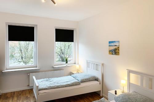 a bedroom with two beds and two windows at Moderne 3 Zimmer Ferienwohnung in Celle