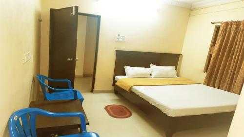 Cette petite chambre comprend un lit et deux chaises bleues. dans l'établissement Vishnu Residency Warangal, à Warangal