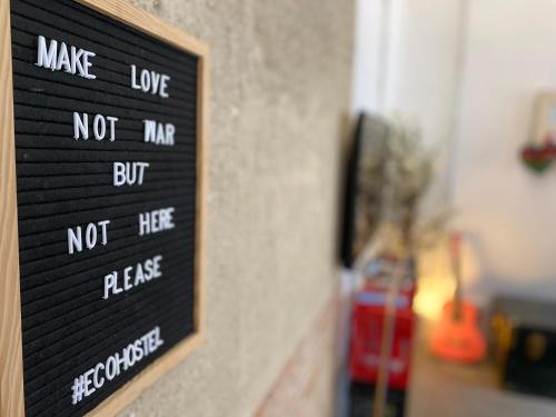 a sign on a wall that says make love not mi but noteperreserved at ECO Hostel in Granada