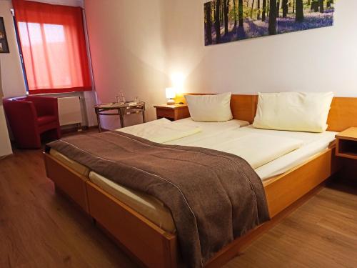 a bedroom with a large bed with a blanket on it at Stadthotel Deggendorf in Deggendorf