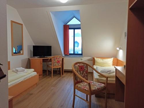 a small room with a bed and a desk and a window at Stadthotel Deggendorf in Deggendorf