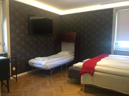 a room with two beds and a flat screen tv at Södra Hotellet in Norrköping