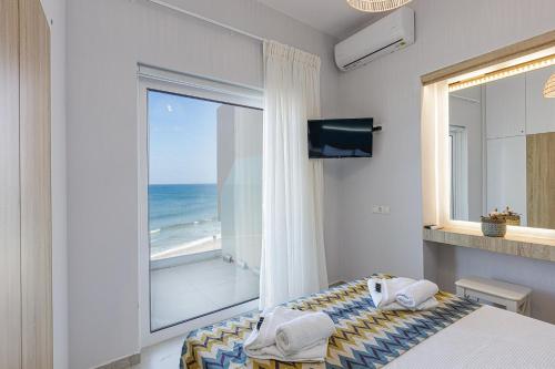 - une chambre avec une grande fenêtre donnant sur l'océan dans l'établissement Seaside Palette Suites, à Réthymnon