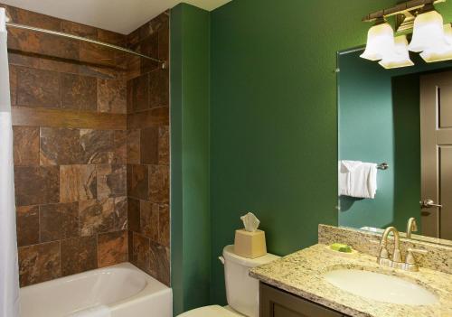 Bluegreen Vacations Christmas Mountain Village, an Ascend Resort في ويسكونسن ديلز: حمام به جدران خضراء وحوض استحمام ومغسلة