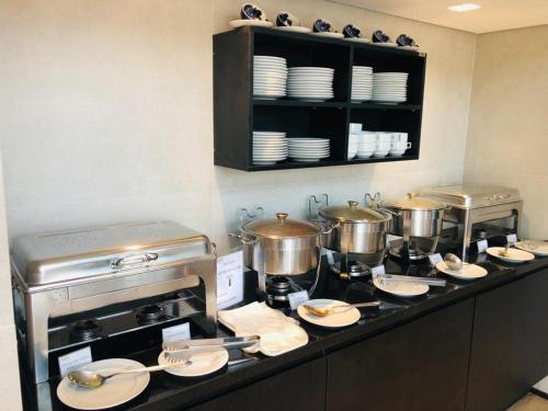 a kitchen with pots and pans and plates on a counter at Astron Suítes Mondial Salvador by Nobile in Salvador