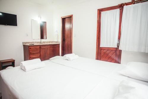 two white beds in a room with a sink and a mirror at Apartamento Duplex Jerusalém I in Porto Seguro