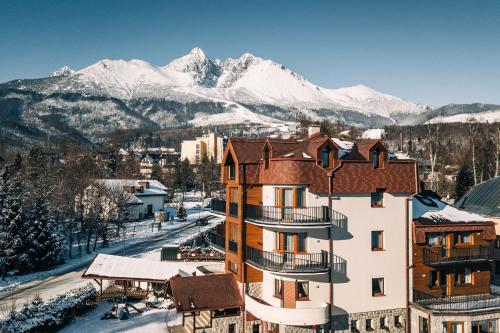 a building with snow covered mountains in the background at APLEND Vila Beatrice in Vysoke Tatry - Tatranska Lomnica.