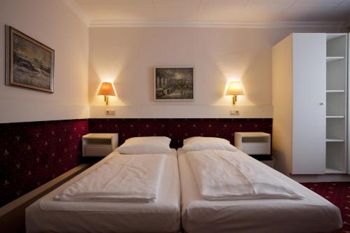 a bedroom with two beds and two lights on the wall at Pension Pharmador in Vienna