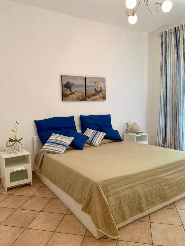 a bedroom with a large bed with blue pillows at Coral sea in San Vito lo Capo