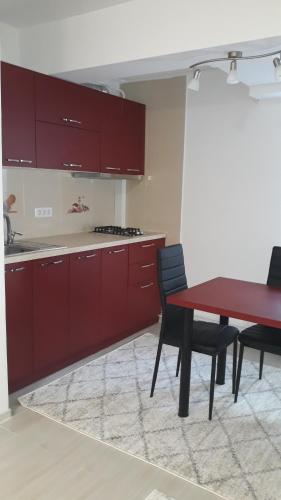 una cocina con armarios rojos y una mesa y sillas rojas. en Irvin Apartament en Iaşi