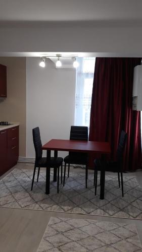 mesa de comedor con sillas y cortina roja en Irvin Apartament en Iaşi