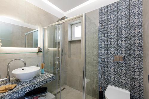 bagno con lavandino e doccia in vetro di Seaside Palette Suites a Rethymno