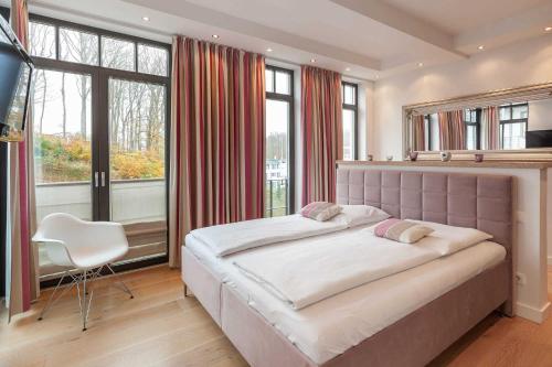 ein großes Schlafzimmer mit einem großen Bett und einem Stuhl in der Unterkunft Villa Claire meerZEIT in Ostseebad Sellin