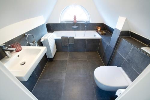a bathroom with a sink and a toilet and a tub at Ferienhaus Strandhafer in Wangerooge