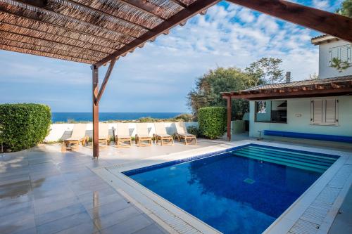 a swimming pool with chairs and a house at House 7, The Artisan Resort in Protaras