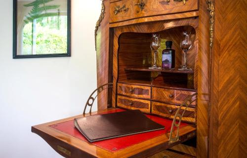 a wooden cabinet with a table with a bottle of wine at Palé Hall in Bala