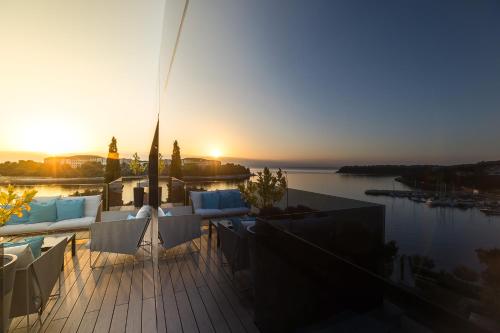 a deck with chairs and the sun setting over a body of water at Boutique Hotel Valsabbion in Pula