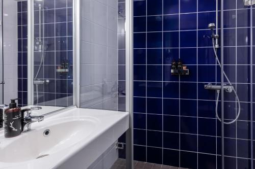 a bathroom with a sink and a shower with blue tiles at Lapland Hotels Kuopio in Kuopio