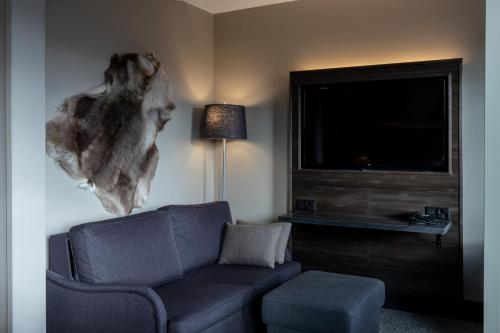 a living room with a couch and a flat screen tv at Lapland Hotels Kuopio in Kuopio