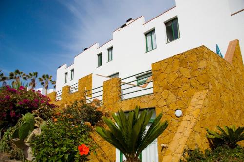 a white building with some plants in front of it at Aparthotel Esquinzo Y Monte Del Mar in Playa Jandia