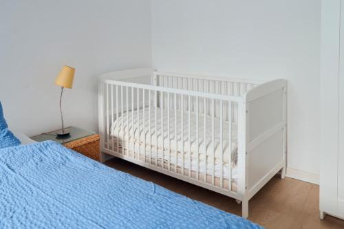 ein weißes Kinderbett in einem Schlafzimmer neben einem Bett in der Unterkunft Ferienwohnung Strand Bucht Moba-Travel in Lübeck