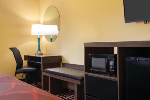 a hotel room with a microwave and a desk with a chair at Hometown Place in Olive Branch