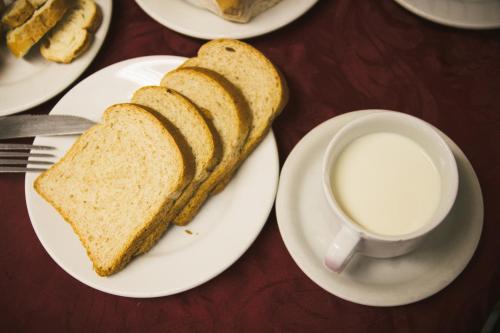 a plate with a sandwich and a cup of milk at Hotel do Papa in Aparecida