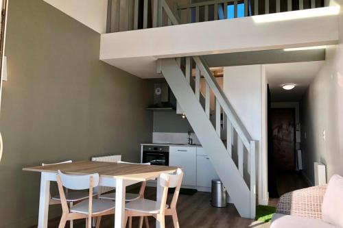 uma sala de jantar com uma mesa e cadeiras e uma escadaria em Magnifique duplex super cosy Vue mer 180 em Ploemeur