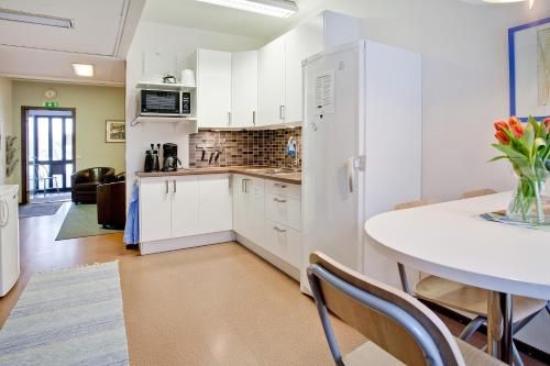 a kitchen with a table and a white refrigerator at Bed's Motell & Rumsuthyrning in Norrköping