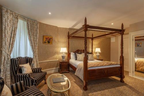 a bedroom with a canopy bed and two chairs at Ballyseede Castle in Tralee