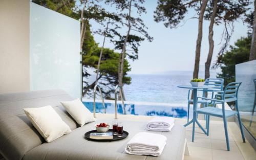 a room with a bed and a view of the ocean at Valamar Carolina Hotel & Villas in Rab