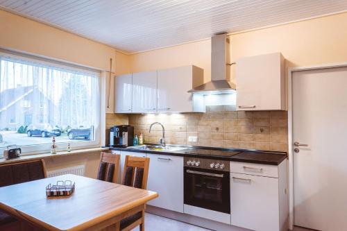 cocina con electrodomésticos blancos, mesa y ventana en Ferienhaus Martens en Schortens
