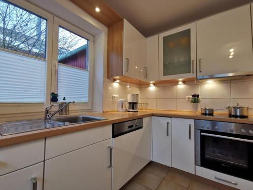 a kitchen with white cabinets and a sink at Ferienhaus Tönsing in Horumersiel