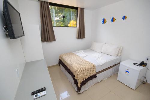 Dormitorio pequeño con cama y TV en Cabanos Suites, en Maragogi