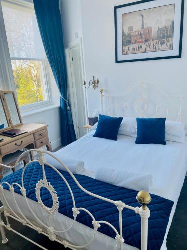 a bedroom with a white bed with blue pillows at Canterbury Hotel Cottages and Apartment's in Canterbury